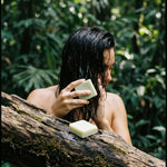 Person with wet hair holding a bar of soap outdoors