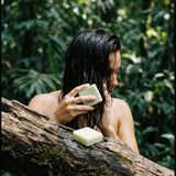 Person with wet hair holding a bar of soap outdoors