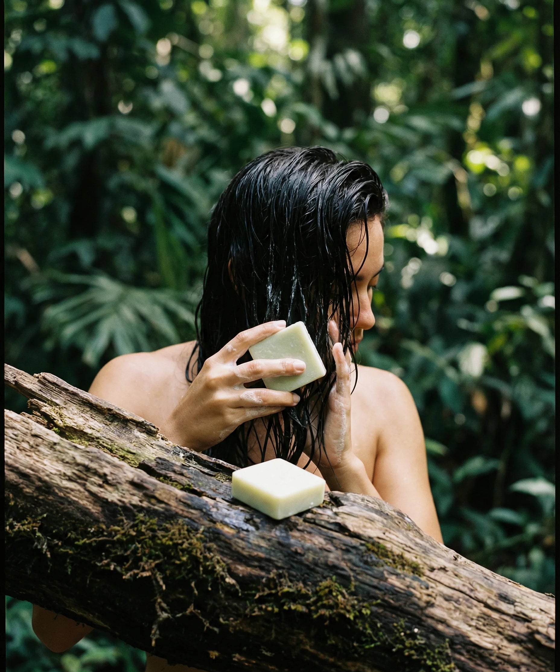 Person with wet hair holding a bar of soap outdoors