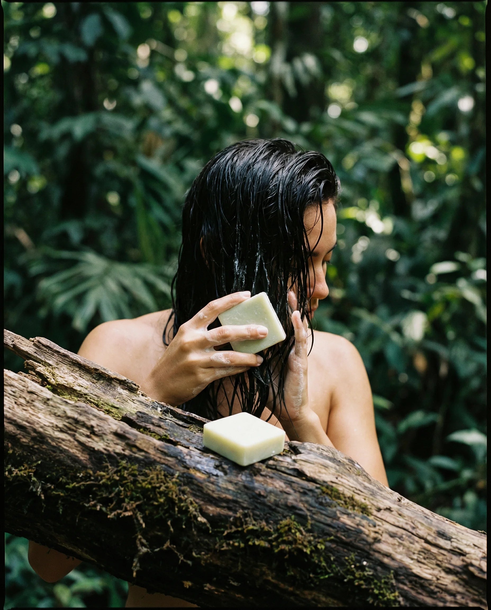 Person with wet hair holding a bar of soap outdoors