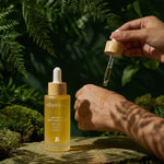 Shveta labs skincare dropper bottle with a hand holding a dropper over a natural background